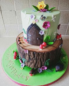 there is a cake that looks like a log with a house on it and flowers around the top