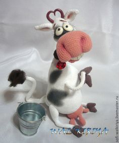 a knitted cow is standing next to a bucket