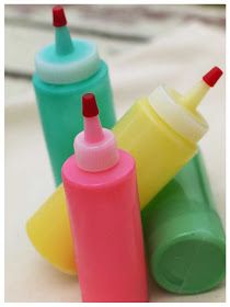 three different colored bottles with toothbrushes in them