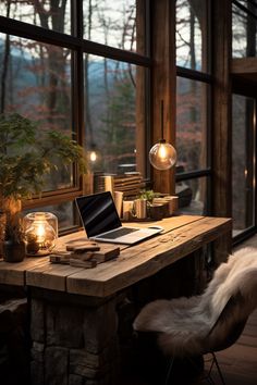 a desk with a laptop on it in front of a large window overlooking the woods