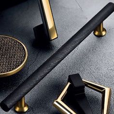 two black and gold door handles on a gray surface with an intricate design in the middle