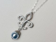 a blue pearl and diamond necklace on a silver chain with an initial charm attached to it