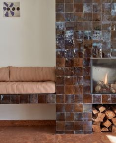 a living room with a fire place next to a couch and fireplace covered in logs