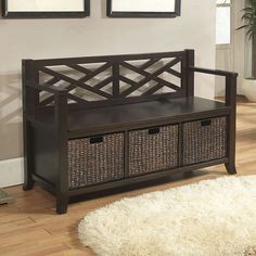 a wooden bench with baskets underneath it on the floor next to a rug and framed pictures