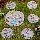 four personalized stepping stones in the grass with flowers and butterflies on them, sitting next to each other