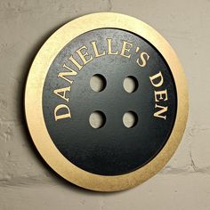 a black and gold sign that says danielle's den on the side of a wall