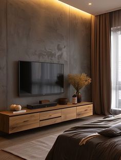 a large flat screen tv sitting on top of a wooden entertainment center next to a window