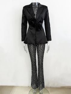 a mannequin wearing a black suit and polka dot pants with a rose on the lapel