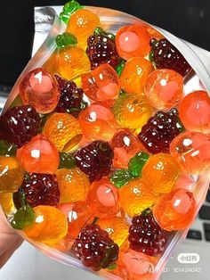 a person holding up a glass bowl filled with gummy bears