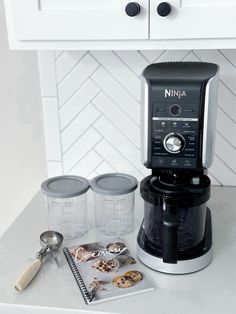 a coffee maker sitting on top of a counter next to jars and measuring spoons