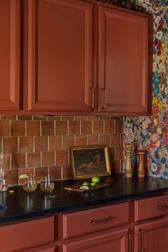 a kitchen with red cabinets and colorful wallpaper on the backsplash is pictured in this image