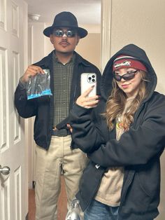 a man and woman standing in front of a door taking a selfie with their cell phones