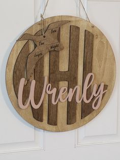 a wooden sign hanging on the side of a door that says, wrenly with an image of a bird