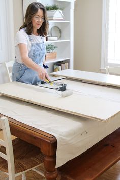 a woman sanding wood on top of a table