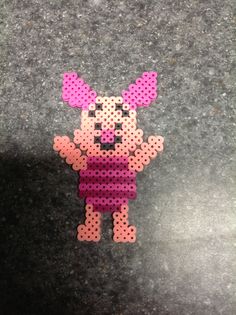 a pink and black dog made out of perforated beads on the ground,