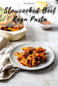 a white plate topped with pasta next to a casserole dish filled with meat