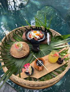 an outdoor table with food and drinks on it next to a pool in the background