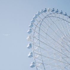 an airplane flying in the sky near a ferris wheel