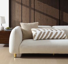 a white couch sitting on top of a hard wood floor next to a table with a lamp