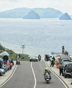 motorcyclists and cars on the side of an ocean road