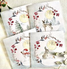 four christmas cards with deer, holly wreaths and moon in the sky on white paper