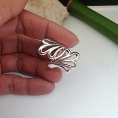 a hand holding a silver ring on top of a table