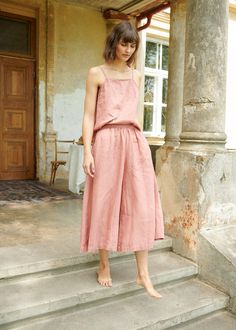 "The Clementine palazzo is the right choice for warmer days when you want to give a romantic touch to your look. The pants boast a cropped hem, in-seam pockets and a flattering gathered skirt-like high waist with an elastic band in the back. IMPORTANT: The Clementine pants have been altered to have a gathered waist instead of the pleated one. If you own a pair with pleated front, note that the pants you will receive will be different. This garment is true to size, and we recommend choosing the s Spring Peach Bottoms For Loungewear, Pink Relaxed Fit Wide Leg Pants For Summer, Summer Pink Relaxed Fit Wide Leg Pants, Pink Linen Bottoms For Spring, Pink Relaxed Fit Linen Pants, Pink Linen Straight Pants, Wide Leg Peach Pants For Spring, Peach Wide Leg Pants For Spring, Peach Wide Leg Bottoms For Spring