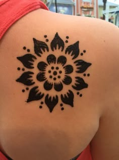 the back of a woman's shoulder with a black and white flower tattoo on it