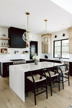 a kitchen with black cabinets and white countertops is pictured in this image, there are four chairs at the center of the island