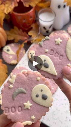 two decorated cookies are being held by someone