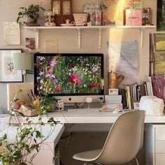 a desk with a computer on top of it next to a potted plant and books