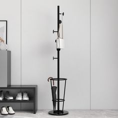 a coat rack with umbrellas and shoes on it next to a bench in a white room