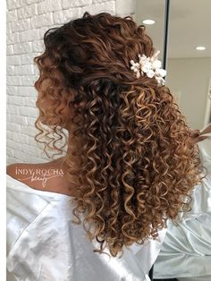 the back of a woman's head with curly hair and flowers in her hair