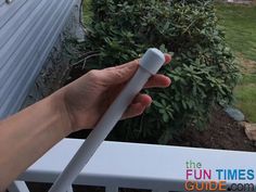 a hand holding an electric toothbrush on top of a white rail near a house