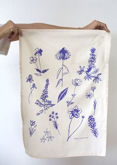 a person holding up a tea towel with blue flowers on it