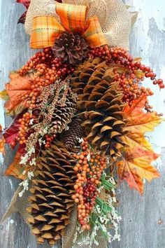 a wreath made out of pine cones, berries and other autumn decorations on a door