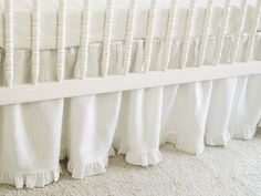 a white crib with ruffles on the bottom