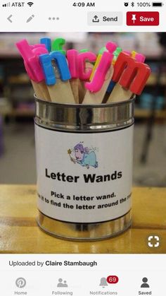 a tin filled with colorful letters sitting on top of a wooden table next to a phone