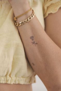 a woman's arm with a rose tattoo on the left side of her arm