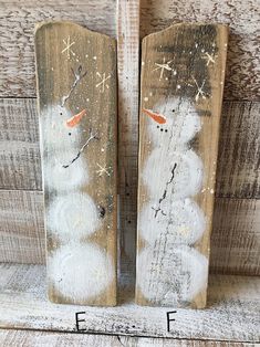 two snowmen painted on wooden planks with the letters f and f below them