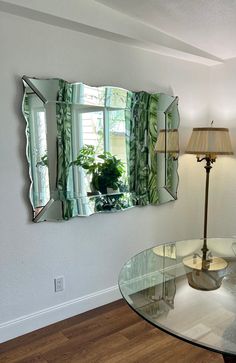 a glass table with a lamp and mirror on the wall