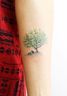 a woman's arm with a small tree and an animal tattoo on the left side of her arm