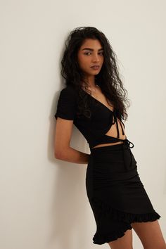 This top is cropped and features short sleeves. It has self tie details and a stretchy material. Chic Short Sleeve Ruched Crop Top, Chic Ruched Short Sleeve Crop Top, Chic Fitted Crop Top With Tie Waist, Fitted Ruched Short Sleeve Crop Top, Fitted Cropped Tie Waist Crop Top, Black Short Sleeve Elastane Crop Top, Black Elastane Crop Top With Short Sleeves, Trendy Short Sleeve Ruched Crop Top, Trendy Ruched Short Sleeve Crop Top