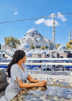 a woman sitting at a table in front of a view of the blue mosques