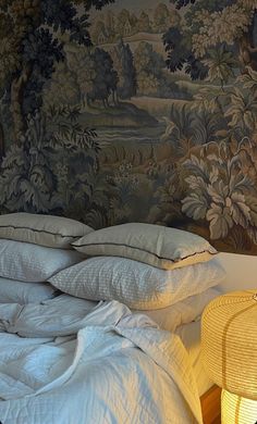 an unmade bed in front of a wall with a tapestry on it's headboard