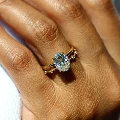 a woman's hand holding a ring with a diamond on it and the middle finger