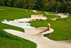 several skateboard ramps in a park with grass and trees