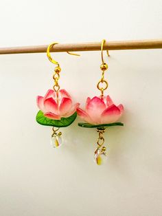 two pink flowers with green leaves hang from gold earwires on a white background