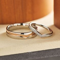 two wedding rings sitting on top of a table next to each other with diamond accents