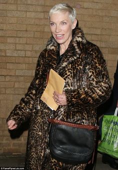 an older woman in a leopard print coat carrying a black purse